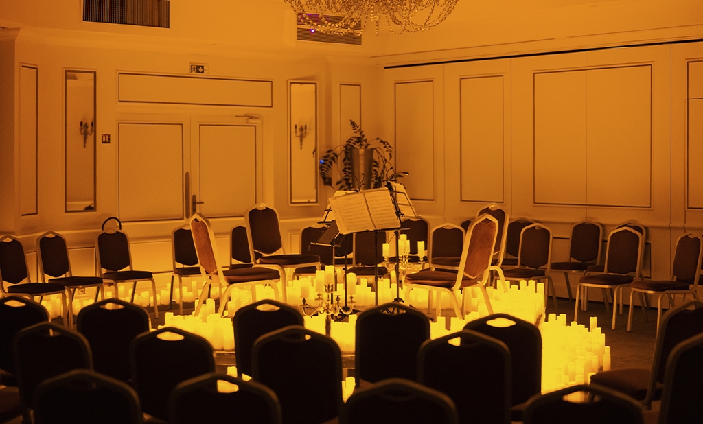 Une salle de l'Hotel Carlton qui accueille un concert Candlelight avec des sièges en velours rouge autour d'un pupitre entouré de plusieurs bougies.