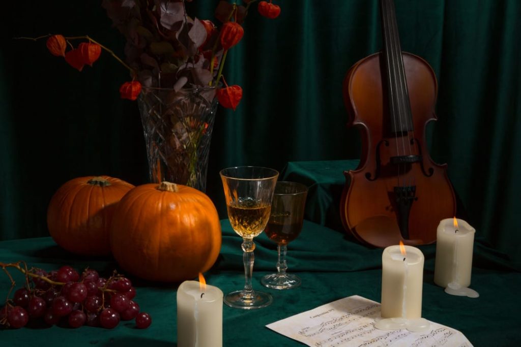 Photo d'une mise en scène pour illustrer un concert Candlelight halloween avec une citrouille, un violon, des bougies et des fleurs fanées